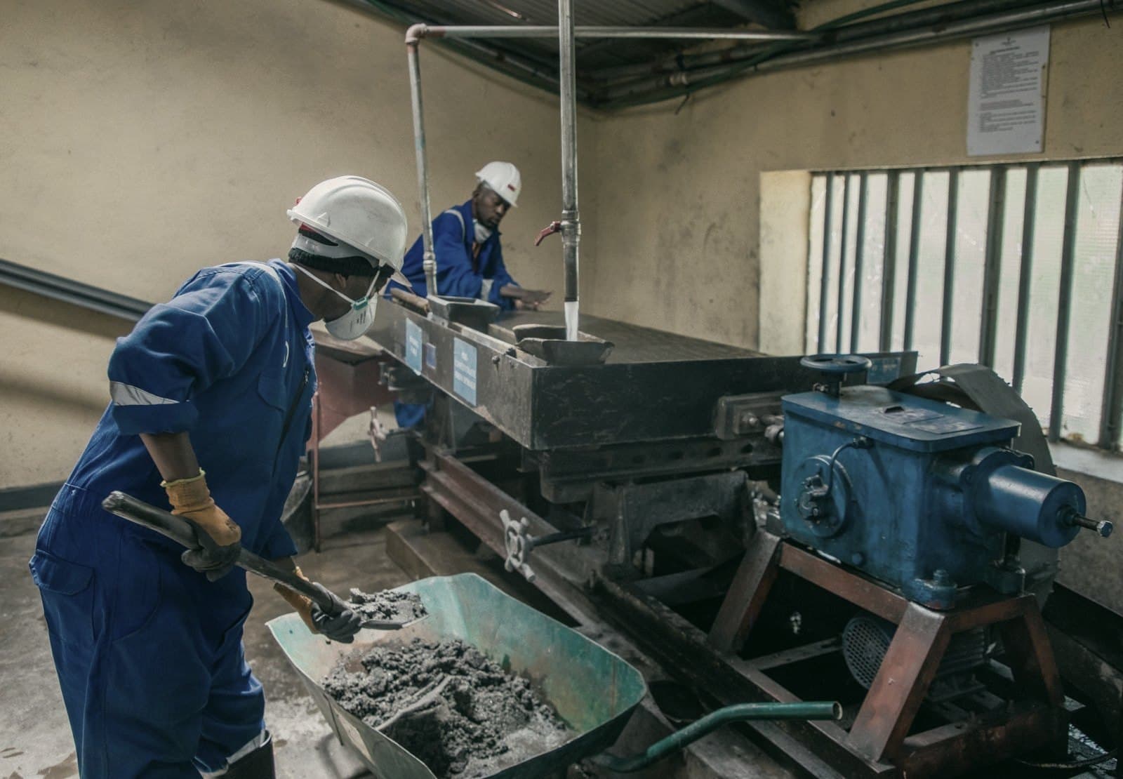 Two factory workers in hard hats operating machinery